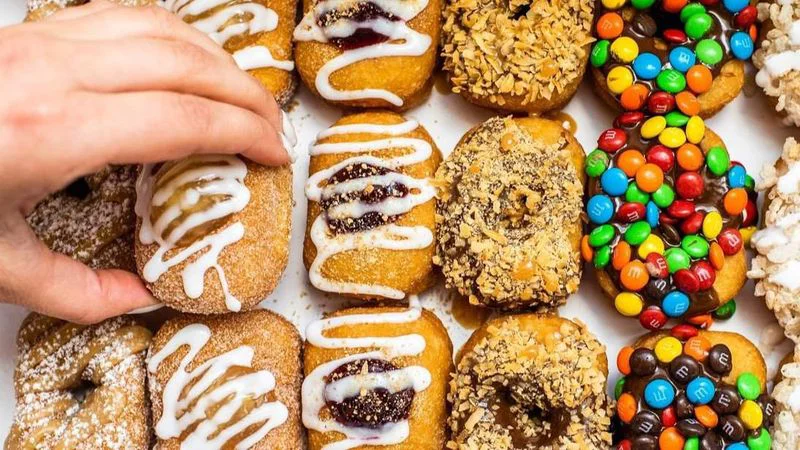 hand reaching in to select from rows of donuts